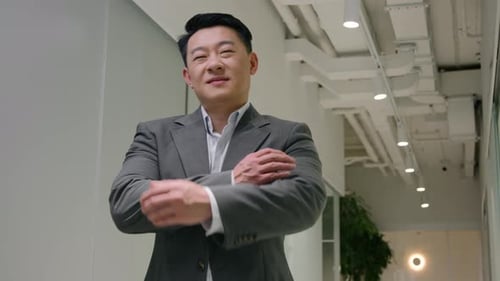 Confident Businessman Smiling with Arms Crossed in Hallway
