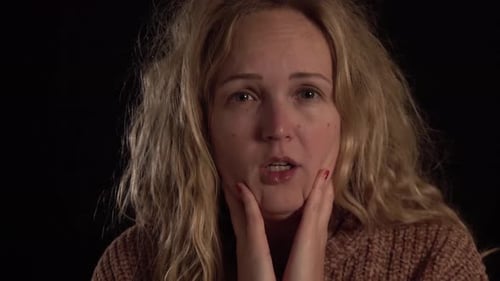 Une femme bâille, elle est fatiguée de sa maladie. Elle a mal à la gorge et elle montre son blanc