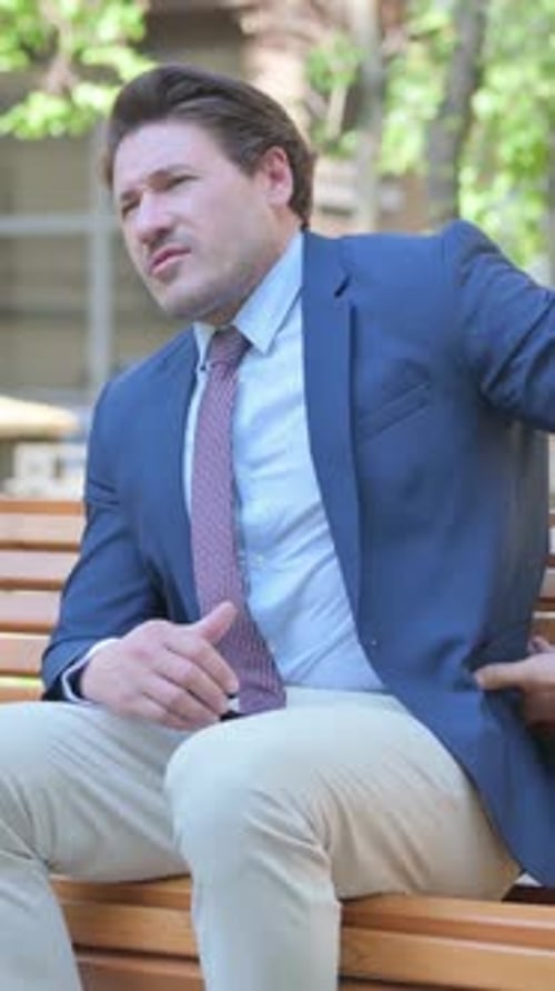 Man Sitting on Bench Rubbing Lower Back