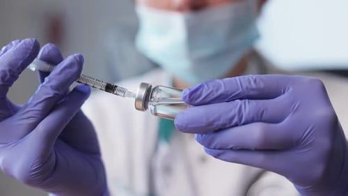 Medical Professional Drawing Vaccine from Vial with Syringe for Patient Injection
