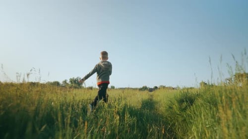 Boy Running Through a Grassy Field on a Sunny Day