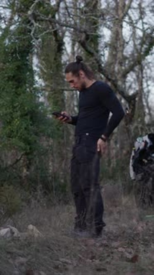 Slow Motion Young Boy Standing in the Forest Consulting His Smartphone While He Prepares Stones and