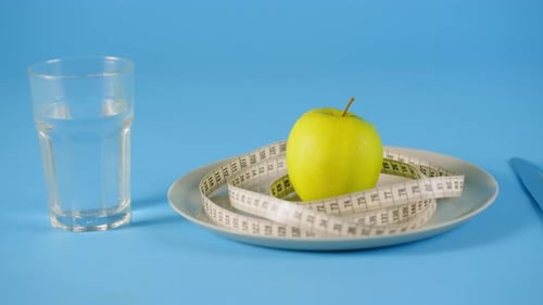 Ripe Green Fresh Apple Wrapped in Measuring Tape on White Plate