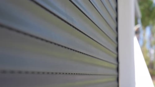 Nahaufnahme eines automatischen Garagentors, das sich bei hellem Sonnenlicht schließt