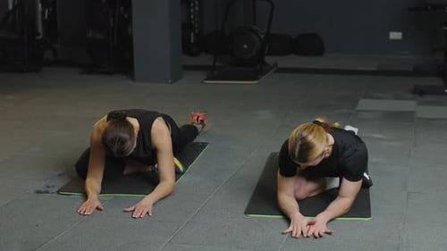 Women stretching and working out together in a gym setting during an afternoon exercise session