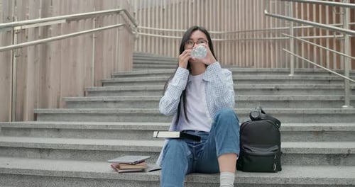 Young Woman Drinking Water on College Steps