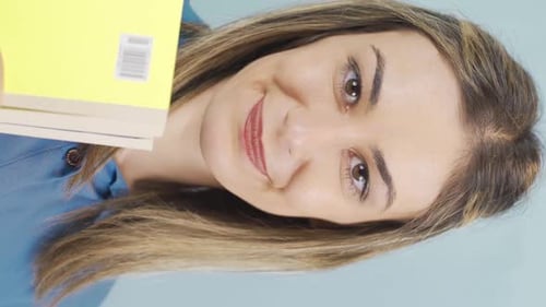 Smiling Woman Holding Books in Vertical Video