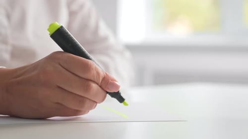 Hand Holding Highlighter Marking Paper in Office