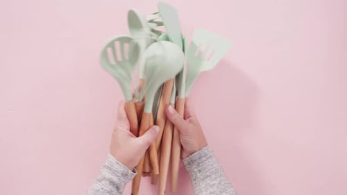 Hands Gathering Cooking Utensils with Wooden Handles