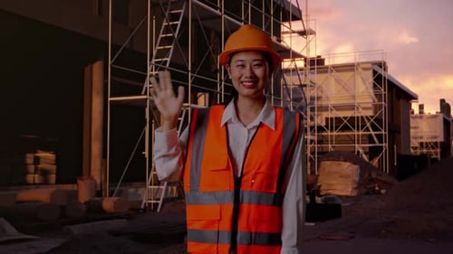 Asian Female Engineer Smiling To Camera And Waving Hand Saying Bye At Building Site