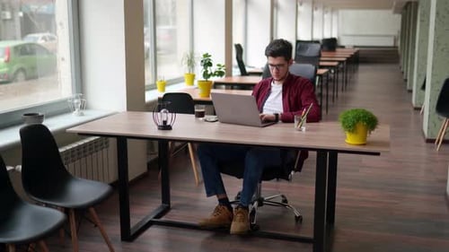 Man Working on Laptop in Modern Open Office