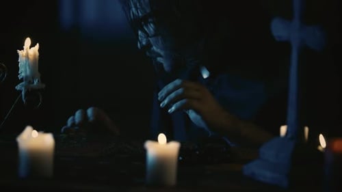 Close Up Video Capturing a Priest Sitting at the Table Anxiously Looking Around with a Candlestick