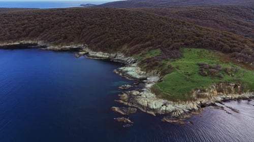 Aerial view of a coastal landscape with green hills and rocky shoreline