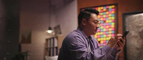 View on Asian Ethnicity Man with Glasses Use Mobile Phone Smiling Scrolling Chatting Social Media at