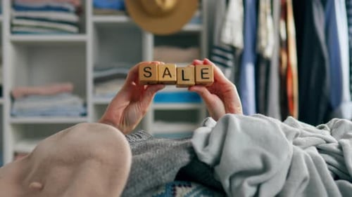 Sale concept in clothing store. The word sales is in the hands of the seller. A seller demonstrates