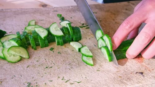 Slicing Fresh Cucumber on Wooden Cutting Board