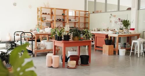 Pottery, ceramic and table in empty workshop with clay objects, design and collection on shelf