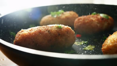 Golden brown croquettes frying in a pan