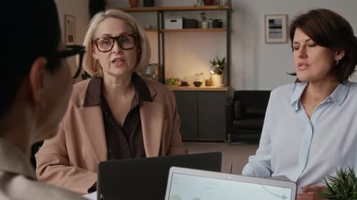 Frau mittleren Alters bespricht Geschäfte mit Kolleginnen im modernen Büro