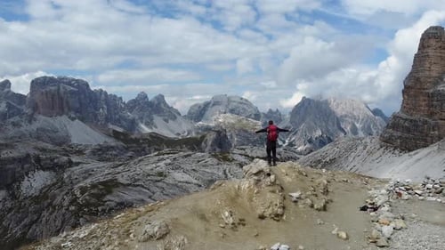 A hiker is standing alone in the mountains and feeling achievement and success after an adventures h