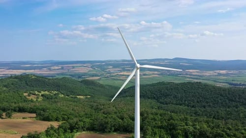 Aerial view to rotor blades of wind turbine in wind park on the hill
