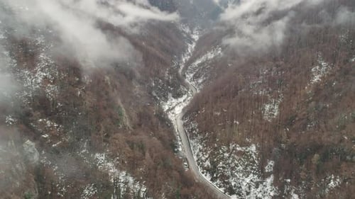 a road between tall rocks with clouds