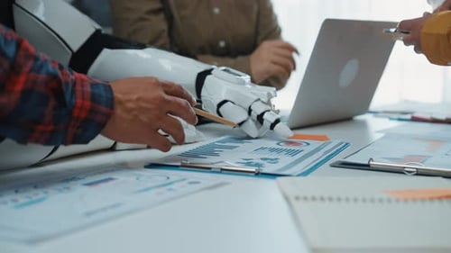 Team Discussing Data with Robot Arm at Table