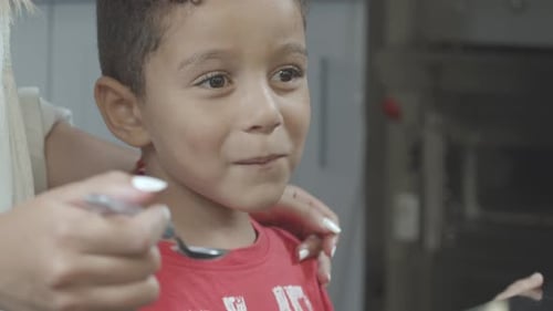 Smiling Child Being Fed Indoors by Adult