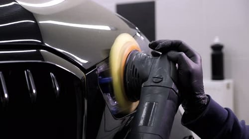 A Car Mechanic Polishing a Black Car Wash Wax and a Polishing Machine