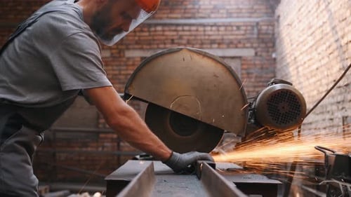 worker cuts metal on a circle and a circular saw. steel pipes and cylindrical blanks for welding.