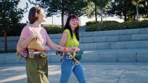 Women Walk Side By Side with Skates on Shoulders Talking