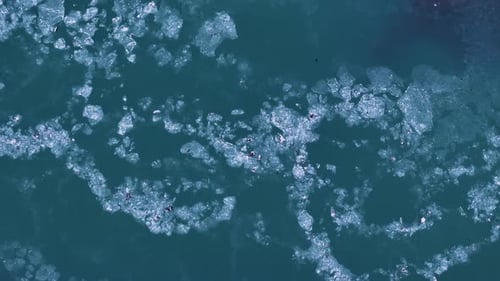 Ice floe swimming in green Icelandic river during daytime in Iceland. Aerial top down shot. Climate