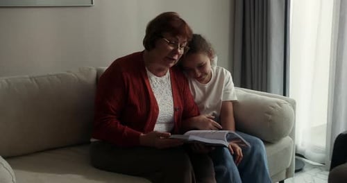 Grandmother Reading to Granddaughter at Home