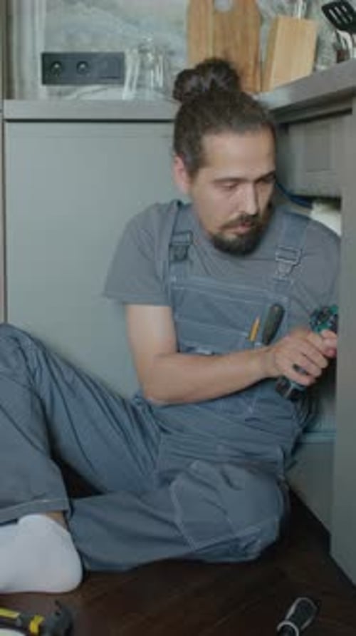 Professional Repairman Fixing Plumbing Pipes with Tools in Kitchen