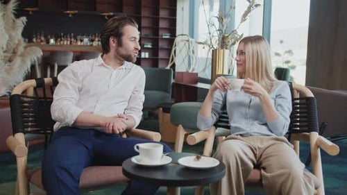 In a Modern Cafe Young Couple Sitting Talking Drinking Coffee Smiling Man and Woman Have