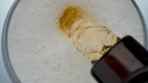 Golden Beer Pouring Into Glass with Frothy Head