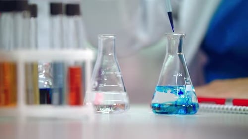 Dripping Chemical Liquid in Glass Flask. Close Up of Chemical Reaction In