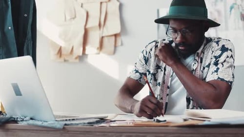 Male Fashion Designer Sketches Designs at His Desk