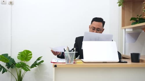 Geschäftsexperte im Anzug, der Finanzberichte und Diagramme an einem modernen weißen Schreibtisch überprüft