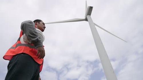 Progressive engineer working with the wind turbine, with the sky as background.