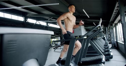 Young Athletic Man Running on Treadmill at Modern Gym