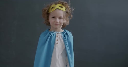 Slow Motion Portrait of Little Boy Wearing Superhero Cape Putting on Mask Smiling Looking at Camera