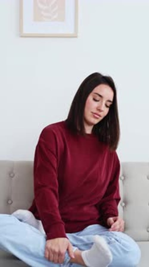 Young Woman Performing Breathing Exercise on Sofa at Home
