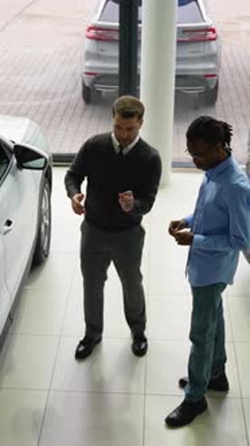 Car Salesman Assisting Customer in Modern Dealership Showroom