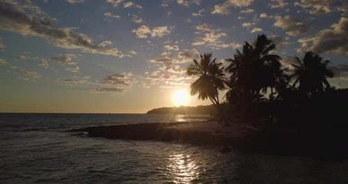 Aerial view of a magnificent sunset landscape: an island with white beach, crystal clear sea, palm