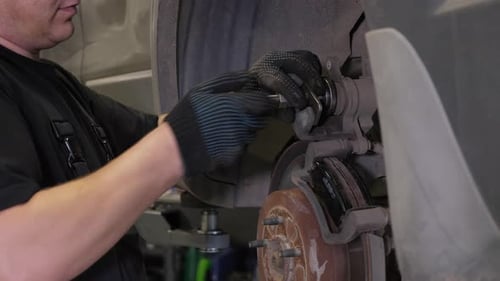 Closeup of a Mechanic Unscrewing a Wheel From a Car Lifted on a Lift