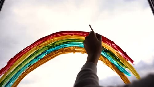 Child Draws Colorful Rainbow on Bright Window