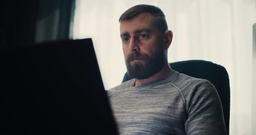 Focused Stock Exchange Broker Monitoring Exchange Market Charts Using Laptop Computer