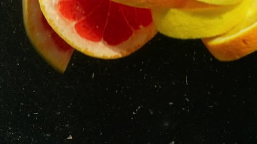 Citrus Fruit Slices Falling into Clear Liquid