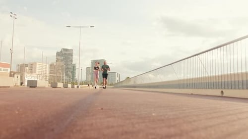 Young joyful active couple jogging together along beautiful seafront. Ground focus